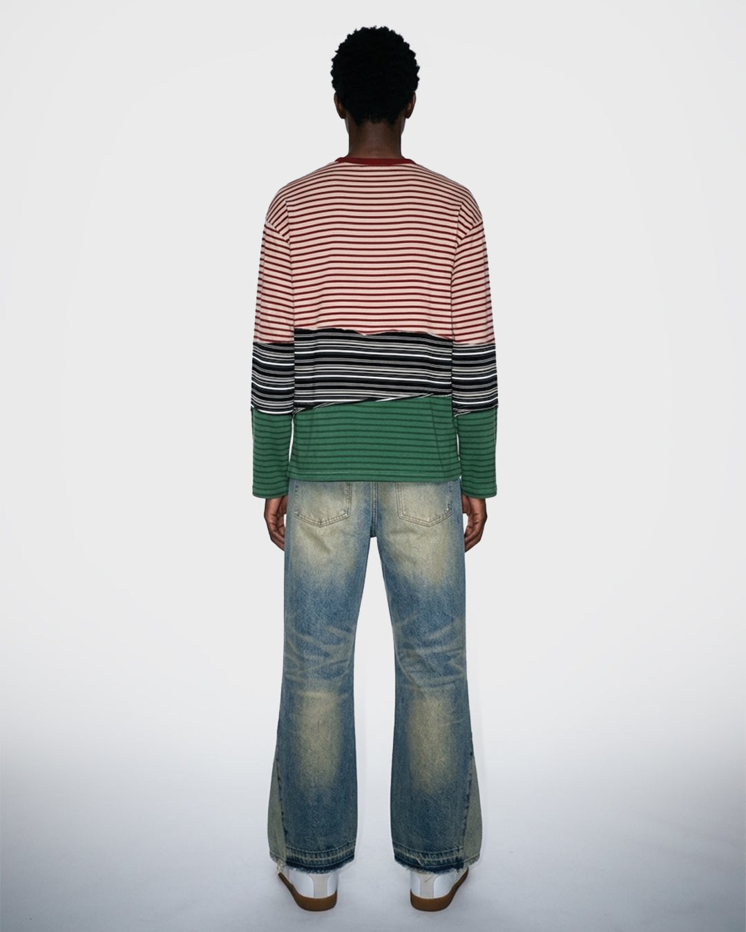 Person wearing a striped long sleeve t-shirt and jeans on a white background